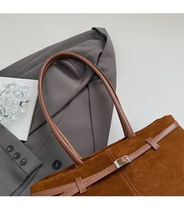 Grand sac cabas en daim marron foncé avec ceinture, assorti à un blazer et un livre