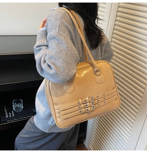 Detail view of large beige shoulder bag with silver eyelet straps and smooth retro texture
