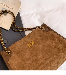 Detail of vintage gold clasp on brown quilted suede bag with chain strap