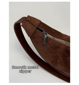 Macro shot of smooth metal zipper and premium suede texture on a brown shoulder bag