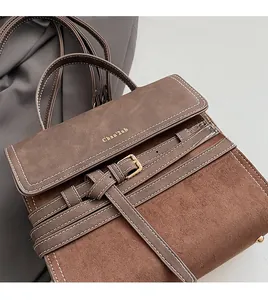 Detail view of brown matte suede texture on crossbody bag with metal buckle and logo