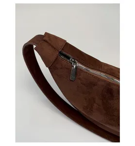 Macro shot of smooth metal zipper and premium suede material on dark brown shoulder bag