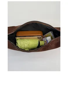 Top view detail of brown suede crossbody bag showing spacious interior with daily items