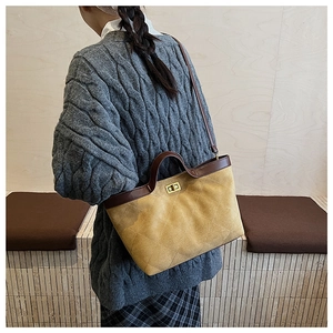 Detail of yellow quilted suede tote bag with brown leather trim worn by a model