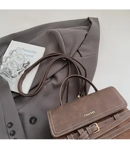 Detail of retro brown frosted leather bag with white stitching and golden logo