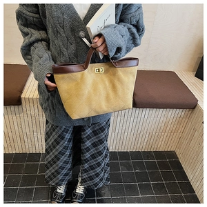 Detail of ginger yellow quilted tote bag with brown leather trim and gold twist lock