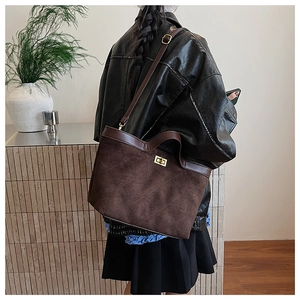 Close-up of quilted suede tote bag with golden twist lock and deep brown leather details