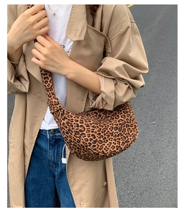 Detail of leopard print crescent crossbody bag on a model wearing a khaki trench coat