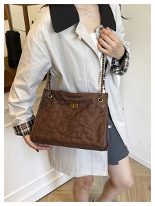 Détail d'un sac cabas en daim marron avec texture matelassée et bandoulière chaîne dorée