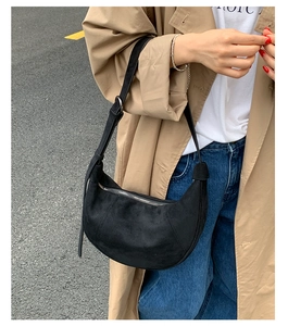 Dettaglio di una borsa hobo in pelle scamosciata nera abbinata a un trench kaki all'aperto