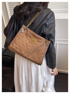Détail d'un grand sac cabas en daim marron avec motif matelassé et chaîne dorée