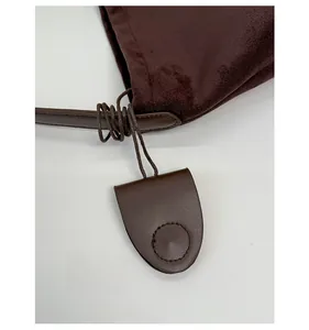 Detail of brown suede tote bag featuring leather tassel charms and fine circular stitching