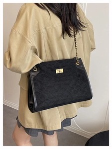 Détail du sac cabas matelassé noir avec fermoir doré et bandoulière en chaîne de cuir