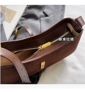 Detail eines glatten Goldreißverschlusses an einer Wildleder-Umhängetasche im Retro-Stil