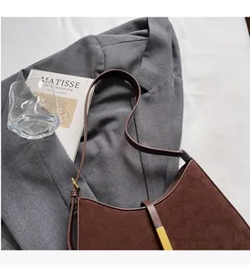 Braune Wildleder-Achseltasche auf grauem Blazer mit goldener Schnalle und Deko