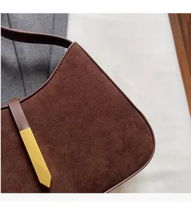 Detailansicht der dunkelbraunen Wildledertasche mit goldener Metallspitze am Lederriemen
