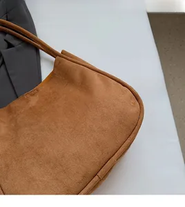 Detailed close-up of brown suede material texture and reinforced stitching on tote bag