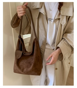 Detail of deep brown suede tote bag featuring sleek shoulder strap and minimalist stitching