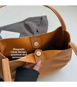 Detail of the magnetic buckle closure on a brown suede leather tote bag with sturdy stitching