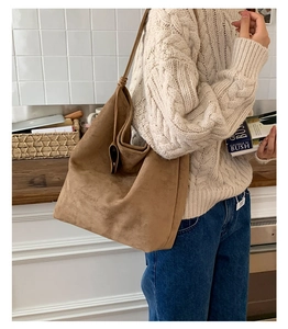Brown suede tote bag detail with knotted strap and metal hardware on a female model