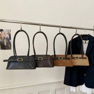 Rij vintage okseltassen van imitatieleer in zwart, bruin en beige hangend aan een rek