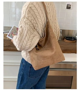 Rear view of model wearing a large brown suede hobo bag in a cozy home kitchen