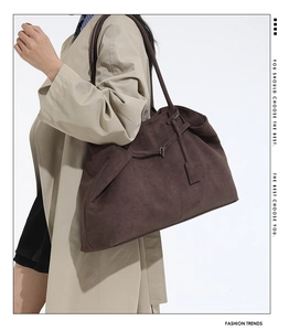 Grand sac cabas en velours marron porté à l'épaule avec une bandoulière fine et bijou