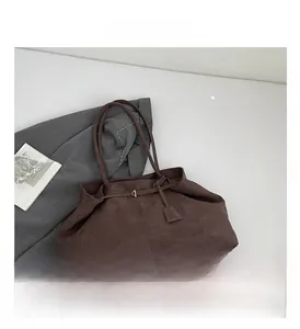 Detail view of large dark brown suede tote bag with slim shoulder straps on flat lay
