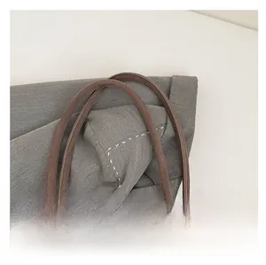 Detailed close-up of dark brown suede handles and high-density gray canvas texture