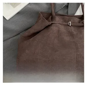 Close-up of deep brown suede fabric texture and metallic D-ring buckle on tote bag