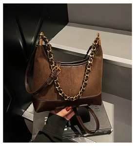 Close-up of vintage brown suede stitching and chunky gold chain strap on the bag