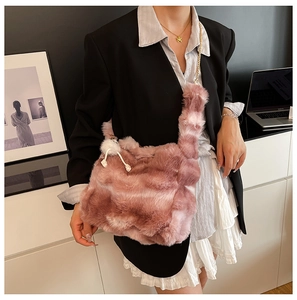 Detail of pink faux fur tote bag with striped texture and soft pompom charm accessory