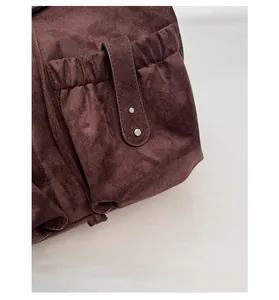 Detail of the side pocket on a vintage dark brown suede backpack with metal rivets