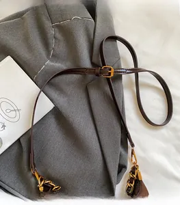 Close-up of adjustable dark brown leather strap with golden chain on shoulder bag