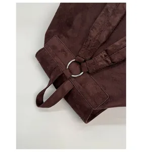 Detail of metal ring buckle and reinforced stitching on a brown suede backpack strap