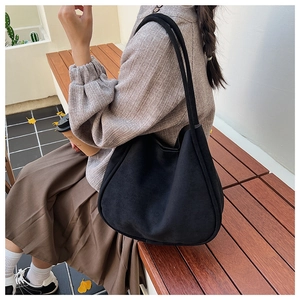 Lifestyle shot of a black minimalist tote bag on a wooden bench in a street setting