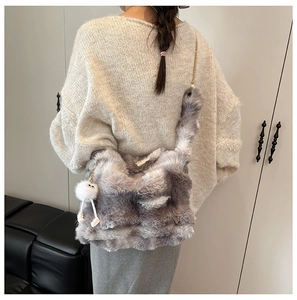 Detail of grey plush chain bag with marble pattern and cute furry doll charm