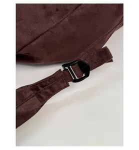 Detail shot of brown suede backpack strap with adjustable black plastic buckle component