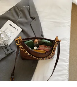 Spacious interior of brown suede and leather shoulder bag with gold chain strap