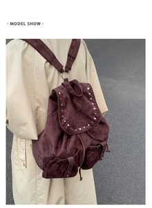 Detail of dark purple suede backpack featuring metal rivets and drawstring closure