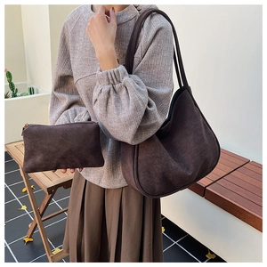 Detail of dark brown suede hobo bag with matching zipper pouch on a wooden bench