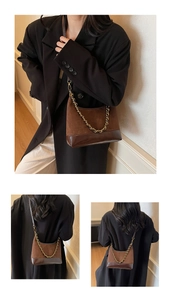 Detail of dark brown suede underarm bag with glossy leather trim and gold chain handle