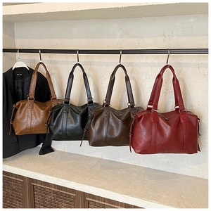 Detailed view of four colorful leather tote bags hanging on a black metal rack in a row
