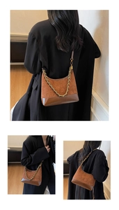Detail of brown suede dumpling bag with gold chain strap and smooth leather bottom