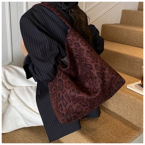 Detailed view of a large leopard print tote bag styled with a professional suit