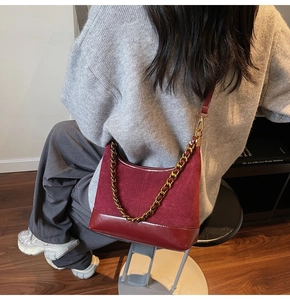 Detailed side view of vintage burgundy suede hobo bag with a gold chain and leather strap