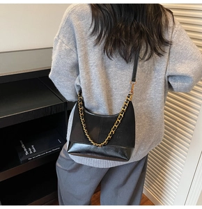 Detail of black matte dumpling bag with chunky gold chain and leather shoulder strap