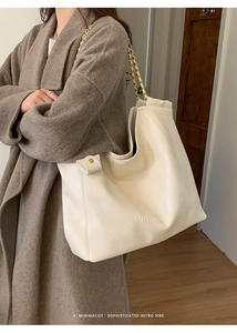 Détail d'un grand sac cabas en cuir blanc crème avec des bandoulières élégantes en chaîne