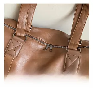 Close-up of brown PU leather tote showing double zipper closure and reinforced stitching