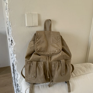 Macro detail of khaki canvas backpack with metal studs and magnetic drawstring side pockets